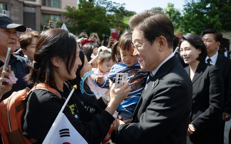 President Lee Jaemyung (right) on June 4 is greeted by his neighbors before leaving his home at an apartment complex in Gyeyang-gu District of Incheon for Seoul National Cemetery. Placards congratulating his election victory were hanged throughout the compound.  