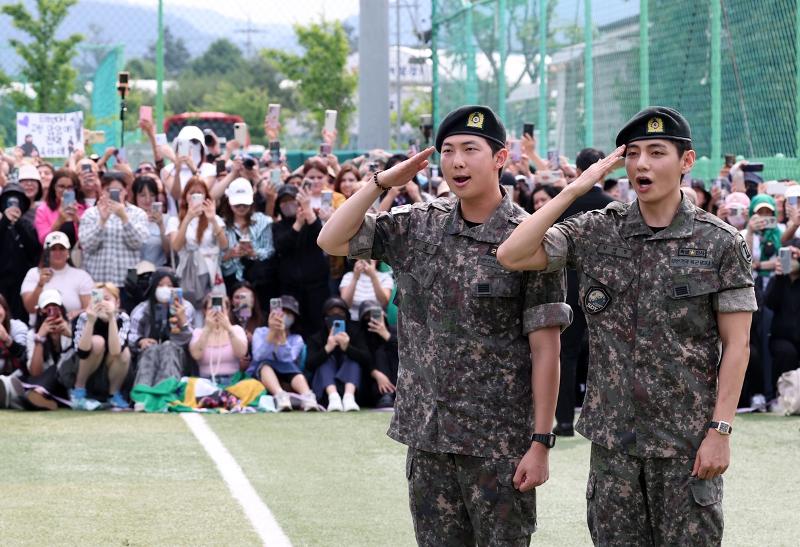 BTS members RM (left) and V on June 10 salute their fans and reporters at an event marking their honorable military discharge at a sports park in the town of Sinbuk-eup in Chuncheon, Gyeonggi-do Province. (Yonhap News)