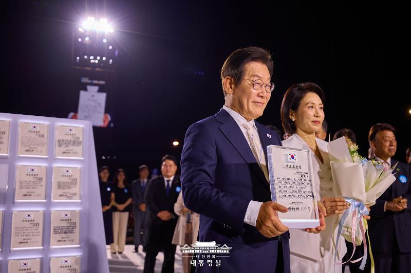 ▲ 이재명 대통령과 김혜경 여사가 15일 서울 세종대로 광화문광장에서 열린 제21대 대통령 국민임명식 '광복 80년, 국민주권으로 미래를 세우다' 행사에서 국민대표 80인으로부터 받은 '국민임명장'을 들어 보이고 있다. 대한민국 대통령실