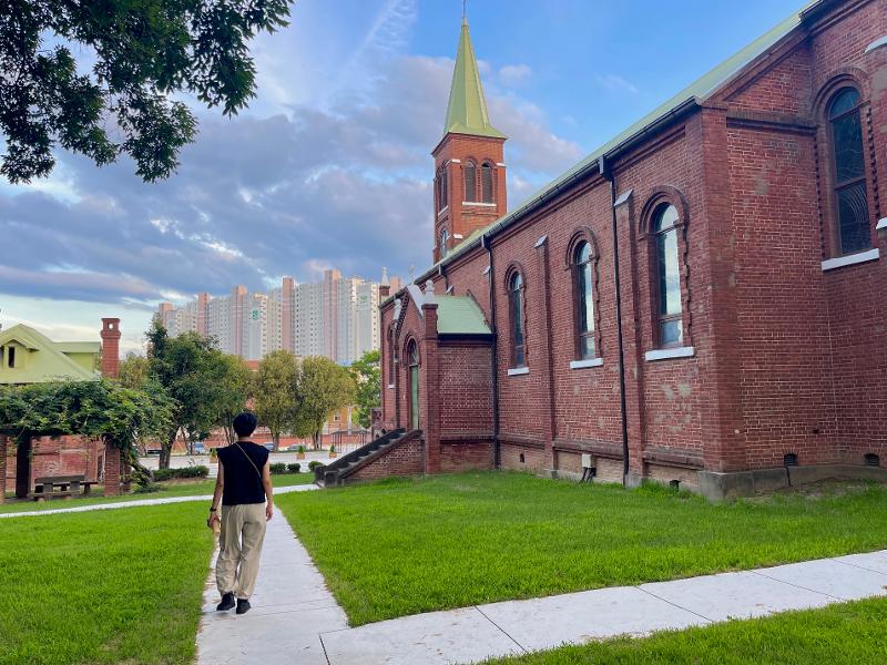 A young man walks on the path next to the old cathedral at the Order of St. Benedict Waegwan Abbey in Chilgok-gun County, Gyeongsangbuk-do Province.