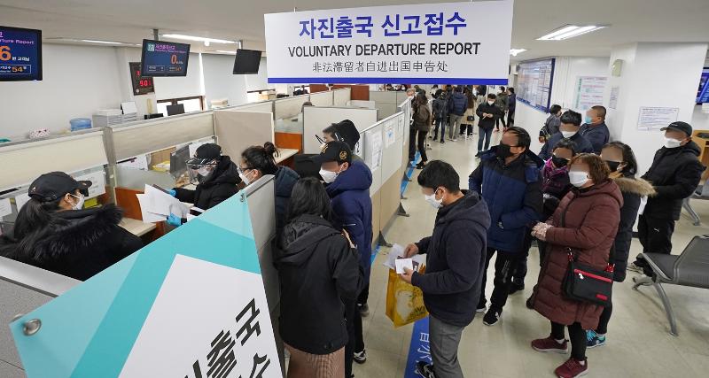 Foreign nationals on the morning of March 6, 2020, wait to report their self-deportation at the Seoul Southern Immigration Office in the capital's Yangcheon-gu District. (Yonhap News)  