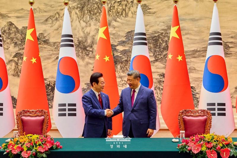 President Lee Jae Myung (left) and Chinese President Xi Jiping on Jan. 5 shake hands at a ceremony for signing a bilateral memorandum of understanding at the Great Hall of the People in Beijing. (Cheong Wa Dae)