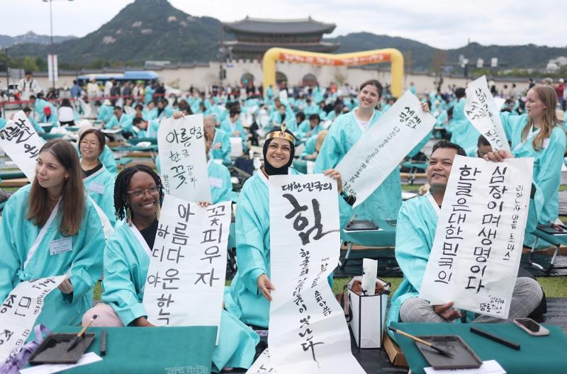 Foreign competitors in a calligraphy contest marking the 579th anniversary of the Korean alphabet Hangeul on Oct. 9, 2025, show off their skills at Gwanghwamun Square in Seoul's Jongno-gu District. (Yonhap News)  