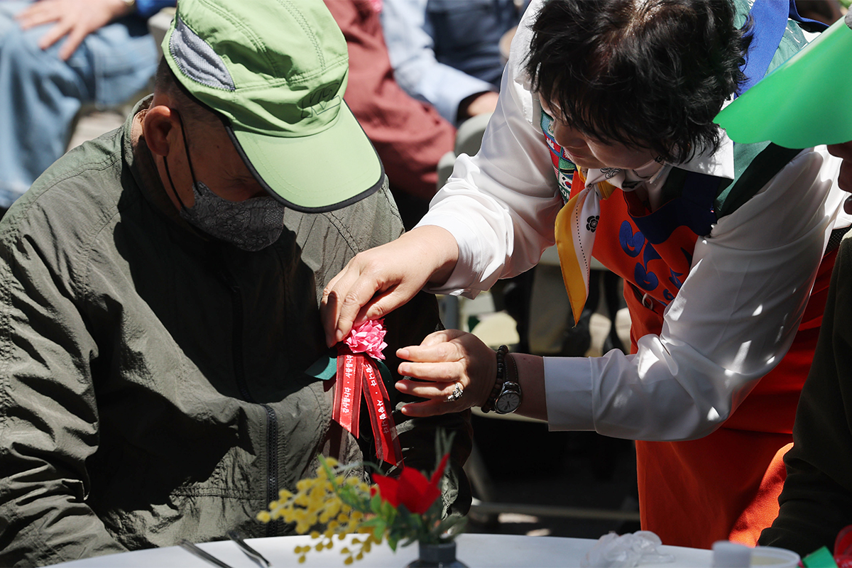 Volunteers on May 8 pin carnations at a Parents' Day event held at the headquarters of the Babfor Sharing Movement, a charity group under the social welfare NGO Dail Community, in Seoul's Dongdaemun-gu District.
