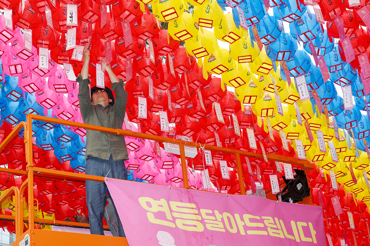 A staff member at Jogyesa Temple in Seoul's Jongno-gu District on May 11 carefully hangs colorful lanterns containing the wishes of people a week before Yeondeunghoe