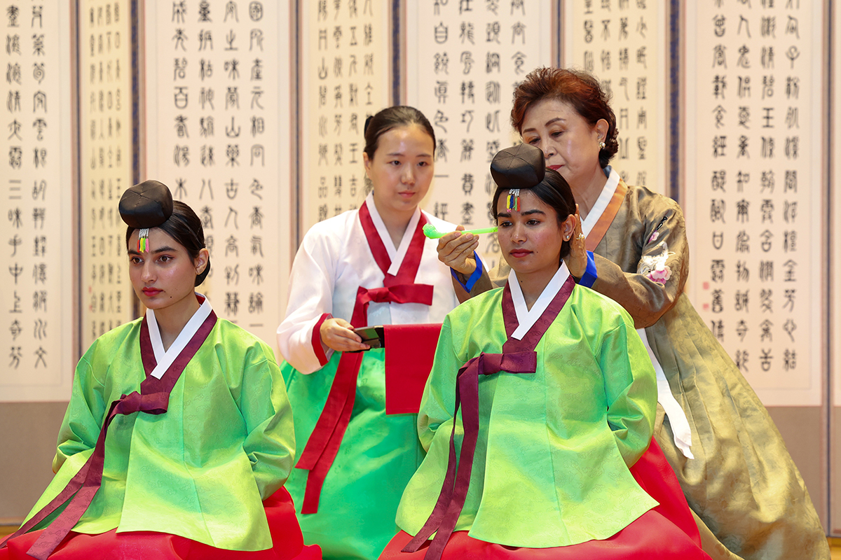 Two international students on May 18 take part in a traditional ritual at a ceremony marking Coming of Age Day at Jicheon Hall of Eulji University in Seongnam, Gyeonggi-do Province.