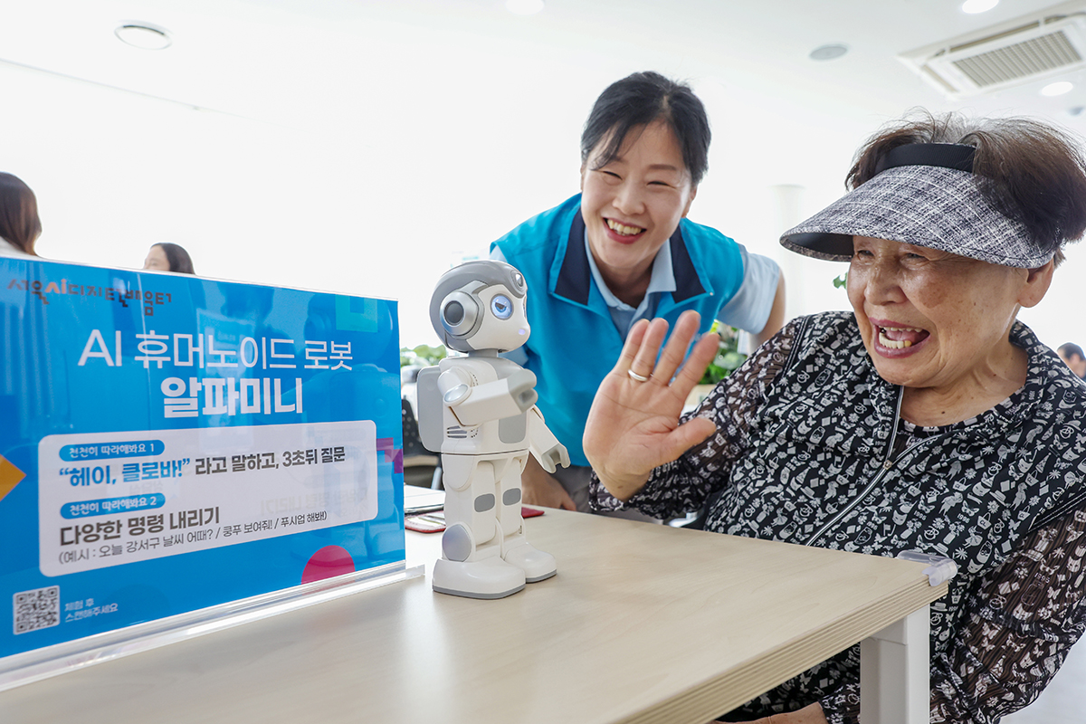 An eldelry woman on May 28 talks with Alpha Mini, an artificial intelligence-powered humanoid robot, at the AI digital learning center of the Gomdalle Culture and Welfare Center in Seoul's Gangseo-gu District. 