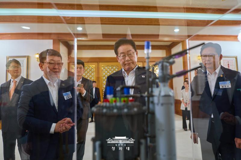 President Lee Jae Myung (second from left in front row) on Aug. 12 looks at a model of a container ship equipped with an SMR before the meeting on the seven SEEDs for future growth at Cheong Wa Dae in Seoul.  