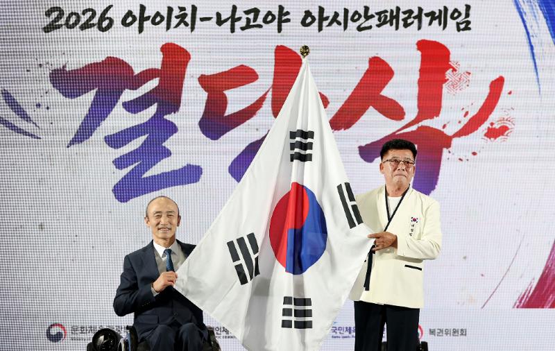 Park Heung-sik, head of the national delegation to the Aichi-Nagoya Asian Para Games in Japan, on Oct. 6 holds the national flag alongside Korea Paralympic Committee President Jung Jin-owan at the launching ceremony for the tournament at the committee's Icheon National Training Center in in Icheon, Gyeonggi-do Province. 