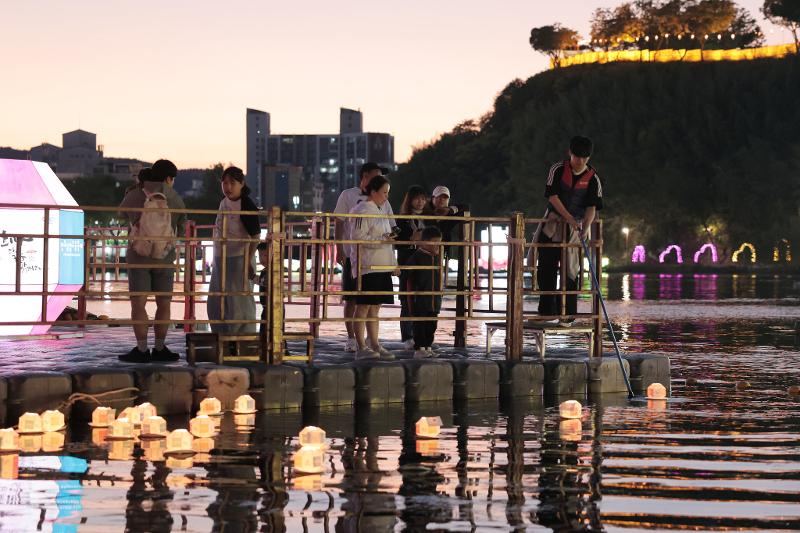 People on Oct. 13 watch floating lanterns drift down the Namgang River while making wishes at the Jinju Namgang Yudeung Festival in Jinju, Gyeongsangnam-do Province.