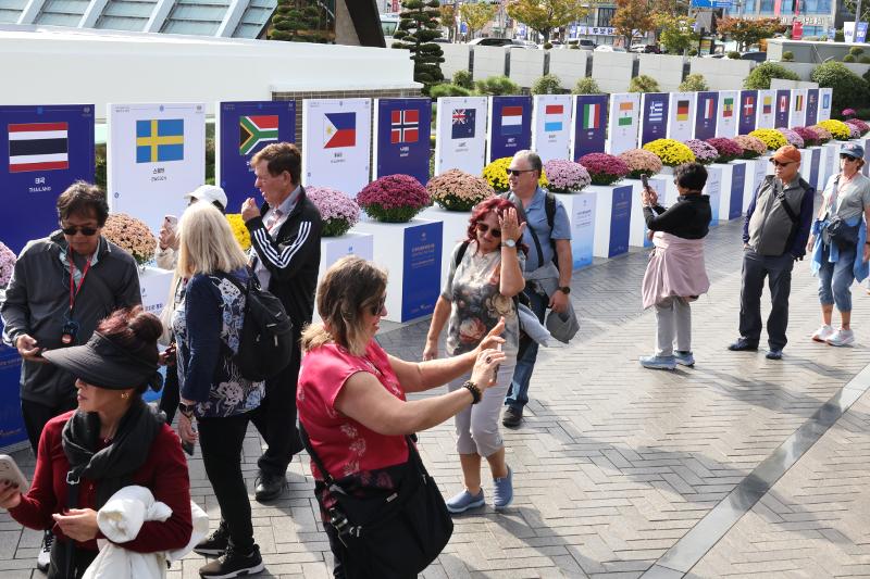 Visitors on Oct. 23 look at the national flags and flowers of the 22 countries that sent troops for the 1950-53 Korean War at the United Nations Memorial Cemetery of Korea in Busan